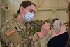 Specialist Jennifer Phillips, a combat medic with the Michigan Army National Guard’s Task Force Red Lion COVID-19 vaccination/testing team, administers the vaccination to employees and their 
