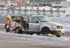 Crews with Central Mat-Su Fire Department clean up the scene after a two-vehicle collision at the intersection of the Parks Highway and Main Street in Wasilla Monday afternoon that sent three