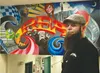 Full-time artist and custodian Stefan Wilson stands in front of a mural he painted above a stairwell in Larson Elementary School. Wilson said one reason he chose to incorporate fictional char