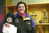Sharlotte Sandstede was the 2003 Alaska Airman of the Year,
races cars, wears silly hats and takes care of children. Sandstede,
in her racing suit, holds up her flight suit showing a badge fr