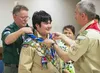 Kim McCann, left, who now serves as the physical security manager at Kure Pier 6 in Japan, places an eagle scout neckerchief on his son, Ian, during a ceremony in 2014. McCann said he still v