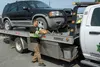 Edison Minyatty, an assistant tow truck operator with JT Towing LLC, tightens a strap to secure a vehicle to a tow truck July 1, 2019, on Joint Base Elmendorf-Richardson, Alaska. Abandoned an
