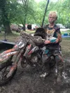 Landin Pepperd stands next to his dirt bike after a muddy race. Landin and his sisters attend Mat Su Central so they can live a non-traditonal life of motocross racing with the goal of a nati