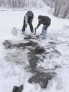 Dave Hopper, left, a board member of Alaskans for Palmer Hay
Flats, and a member of the Department of Environmental
Conservation, right, use a weed burner and absorbent towels to
clean a oil 