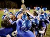 (ROBERT DeBERRY/Frontiersman) Members of the Palmer Moose
football team gather around the Mayors Cup after winning the Potato
Bowl Friday night at Mechetanz Field in Palmer.