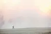 A Division of Forestry fire fighter walks across the Fishhook Golf Course as smoke fills the air from a wild fire Thursday afternoon. ROBERT DeBERRY/Frontiersman.com