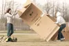 ROBERT DeBERRY/Frontiersman Wasilla’s Kelseay Lund, 14, left,
and Lindsey Boll, 12, fight a strong wind while getting their
cardboard house together for the Family Promise Mat-Su Cardboard
Ci