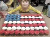 Tezlyn Dwyer stands behind an American Flag made out of cupcakes
at a fund-raiser March 5 to help with her grandfather’s burial
costs. He died on vacation in the Philippines and the family ra