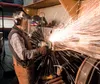 Jerry Cunnington grinds on a tender rail car inside the Kenai Supply building in Wasilla Saturday where the steam locomotive Engine 557 is being restored. The tender car is pulled behind the 