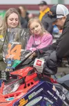 Jody Payton, a rookie, shows the panel display on his snowmachine to family and friends Alexis, 1, and Willow, 6, at the meet and greet tech inspection at the Menard Center on Tuesday. J. Dav
