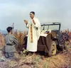 Father Emil Kapaun celebrates Mass using the hood of his jeep as an altar, as his assistant, Patrick J. Schuler, kneels in prayer in Korea on Oct. 7, 1950, less than a month before Kapaun was