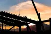ROBERT DeBERRY/Frontiersman A worker is silhouetted against the
rising sun Thursday assembling cross beams for the roof on the
Yenlo Square building, a planned unit development that will prov