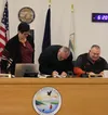 Deputy Mayor Mike Adams, center, signs his Oath of Office certificate following his swearing-in ceremony. He and Mayor Carter Cole, seated, were both re-elected into 1-year terms by the Houst