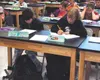 Students Angel Reich, left, and Seaira Reno attend class in one
of the few rooms at Teeland Middle School equipped with tables and
chairs last week. While delays in furniture shipments have c
