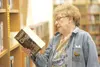 ROBERT DeBERRY/Frontiersman Julia Ede examines a book Thursday
at the Wasilla Public Library. Ede, a Wasilla Friends of Library
board member, disagrees with charging people who live outside c