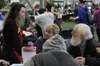 Wasilla High School student Talia Dillard describes the lunch menu for Wasilla residents Catherine Hall and Ted Cessop at Project Homeless Connect in the Curtis D. Menard Memorial Sports Cent