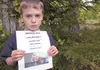 Wyatt Reinhart, 8, holds a flier for his missing service dog, Abby. It was feared the dog may have been taken, but the animal’s body was found Friday in a lake near the family’s home. ROBERT 