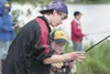 Dalton Moore helps Bear Cub Dixon Hubb, 9, learn to cast during
a Cub Scout outing at Finger Lake Saturday afternoon. (ROBERT
DeBERRY/Frontiersman)