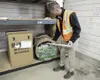 Scott Tarbox, JBER hazardous waste manager, demonstrates the proper placement of a fluorescent lamp in a properly labeled and sealable container at Joint Base Elmendorf-Richardson, Alaska, No
