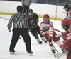 Wasilla defenseman Tyler Lutz skates by the Colony and Wasilla benches to pick up a loose puck during Colony's 3-2 win over the Warriors in the North Star Conference Championships title game 