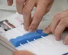 U.S. Air Force Airman 1st Class Kevin Otero, official mail clerk assigned to the 379th Expeditionary Communications Squadron, takes the cotton swab after swabbing the inside of the cheek and 