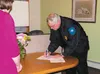 Wasilla Police Chief Gene Belden signs his name on an official document Tuesday, committing his department to three more years of helping address child abuse and neglect along with other stat