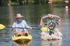 Valley artist Carmen Summerfield positions a floating piece of art made from a rake and recycled materials on Wasilla Lake during a Valley Arts Alliance floating art event Saturday afternoon.