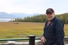 Mike Mahoney stands on his back deck with a view of Joe Redington's boat in the background. Mahoney is among Knik residents who are restoring the boat that was once owned by the man who helpe