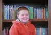 Joel Shelton, a second-grader at Fronteras Spanish Immersion School, smiles while sitting in front of a bookcase at his home. He was diagnosed with leukemia in 2013 and is technically in remi