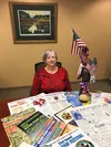Merry Braham, longtime special events coordinator for the Chugiak-EagleRiver Chamber of Commerce, shows off her collection of Bear Paw Festivalposters last Friday on her last day of work. The