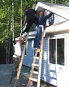 Jarred Culbertson of Louisiana hands Jerad Zabraskie of
Fairbanks a hammer. Aimee Bridges of Arizona helps with the siding
project. Photo by CASEY RESSLER/Frontiersman.