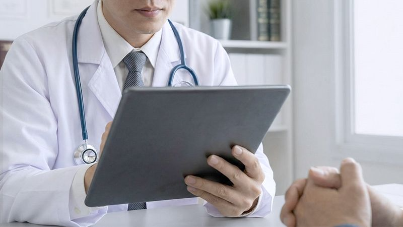 의사가 기록지 또는 태블릿을 보며 판단하고 있는 손과 시선