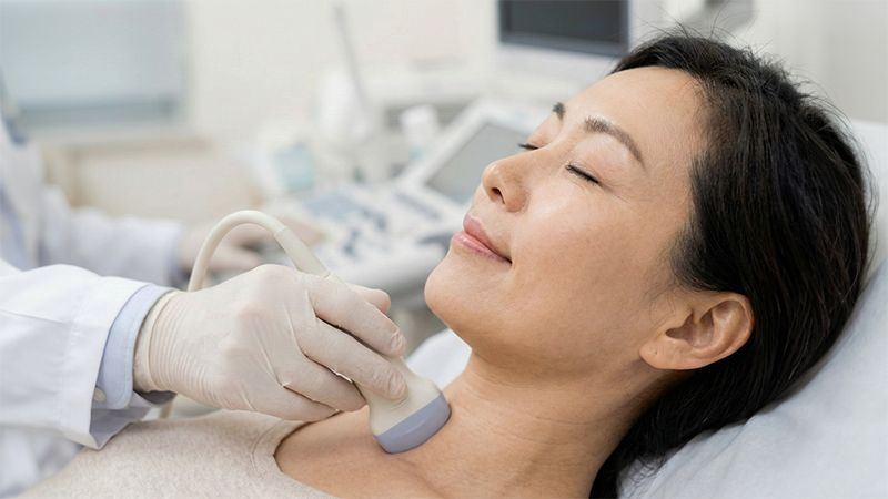 의사가 환자의 목에 초음파 기기를 부드럽게 대고 있는 모습 