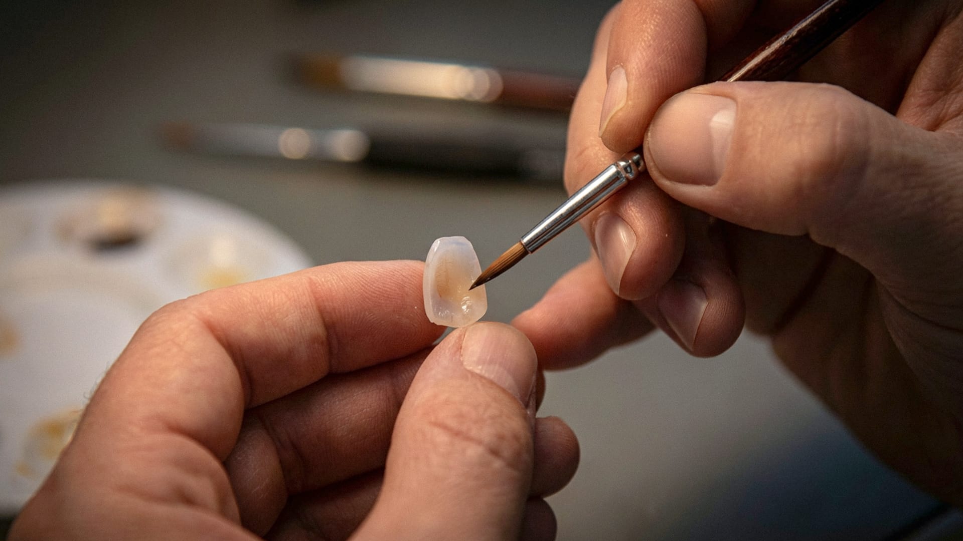 기공용 미세 붓으로 아주 작은 라미네이트 보철물을 섬세하게 다듬고 채색하는 전문가의 손길 클로즈업
