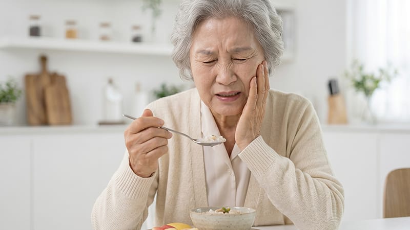 An elderly patient experiencing discomfort in their dental implant while eating a meal