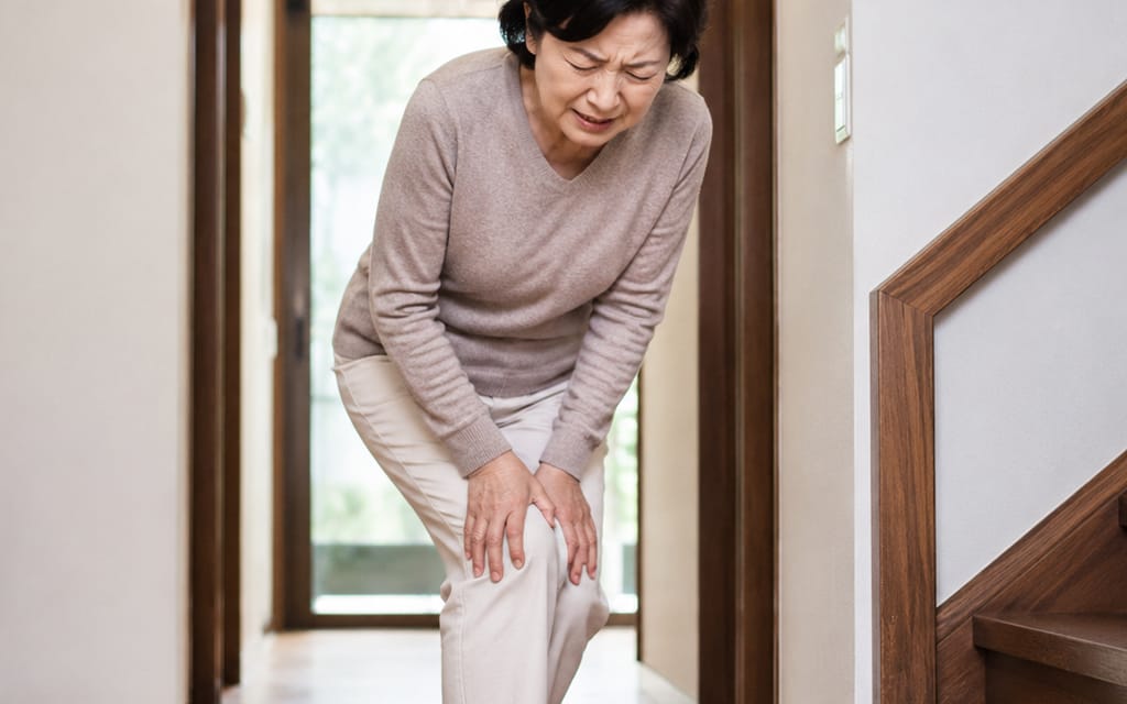 A middle-aged patient holding their pain-stricken knee in discomfort