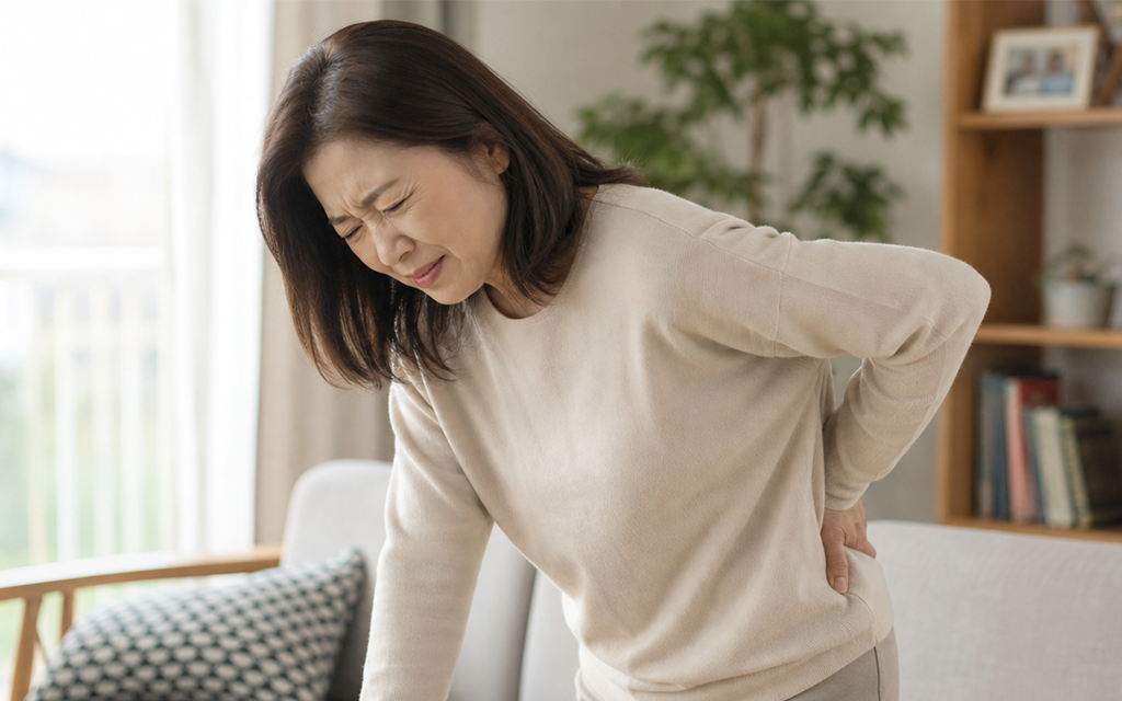 A patient holding their lower back in severe pain