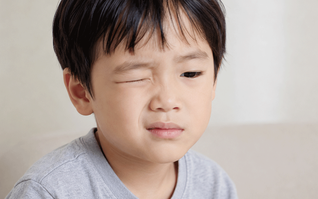 A child squinting their eyes while trying to focus on something