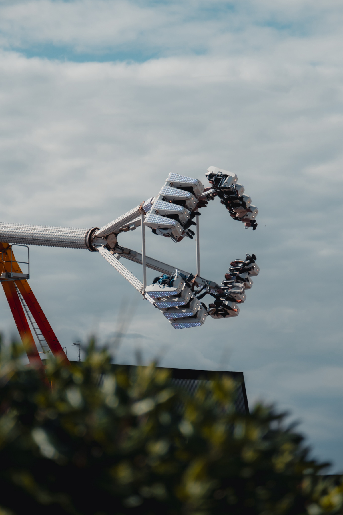 A group of people are being spun upside down on a thrill ride against a cloudy sky backdrop.