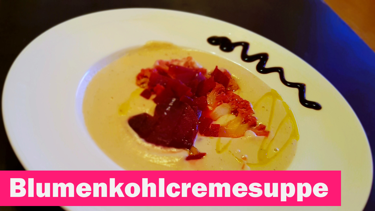 Ein Teller mit Blumenkohlcremesuppe mit einem Rote Bete Herz und Blumenkohlröschen dekoriert.