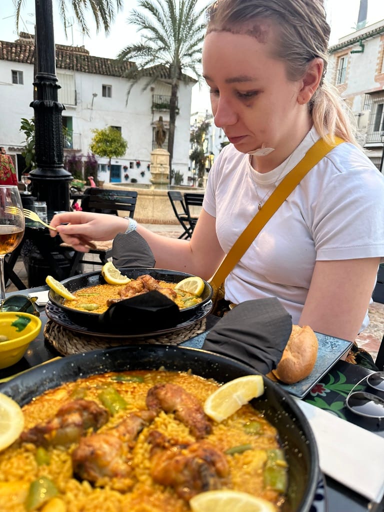 Maisie eyes up a big bowl of paella con pollo in a Marbella town square