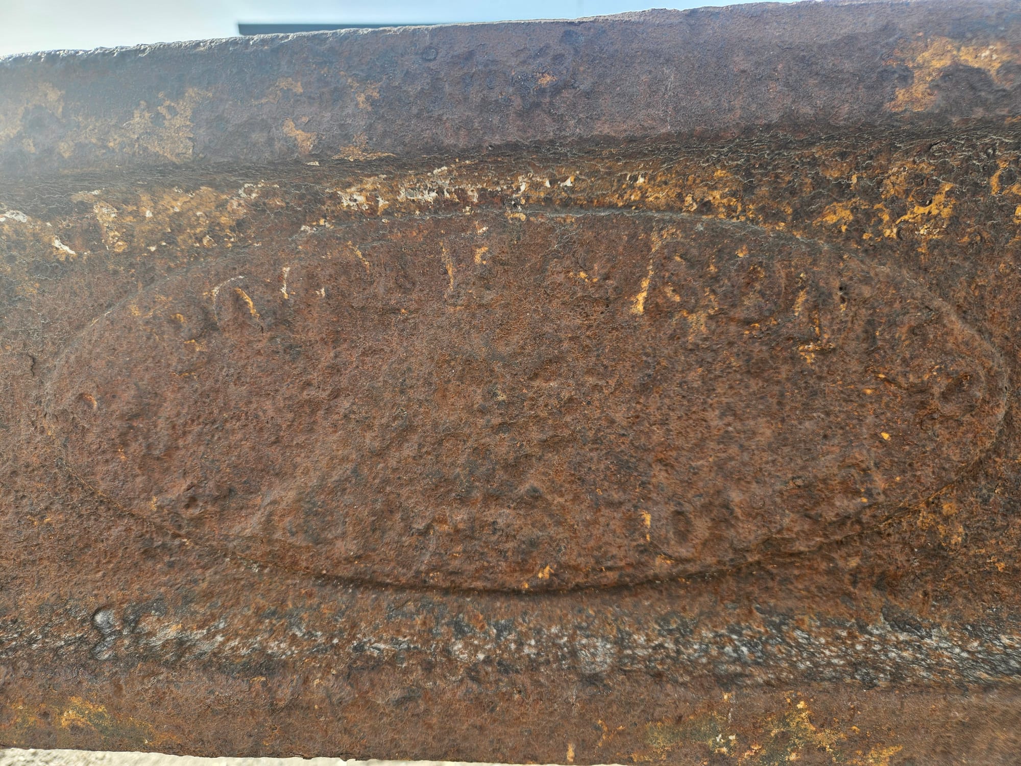 An illegible close up of a rusted iron stamp.