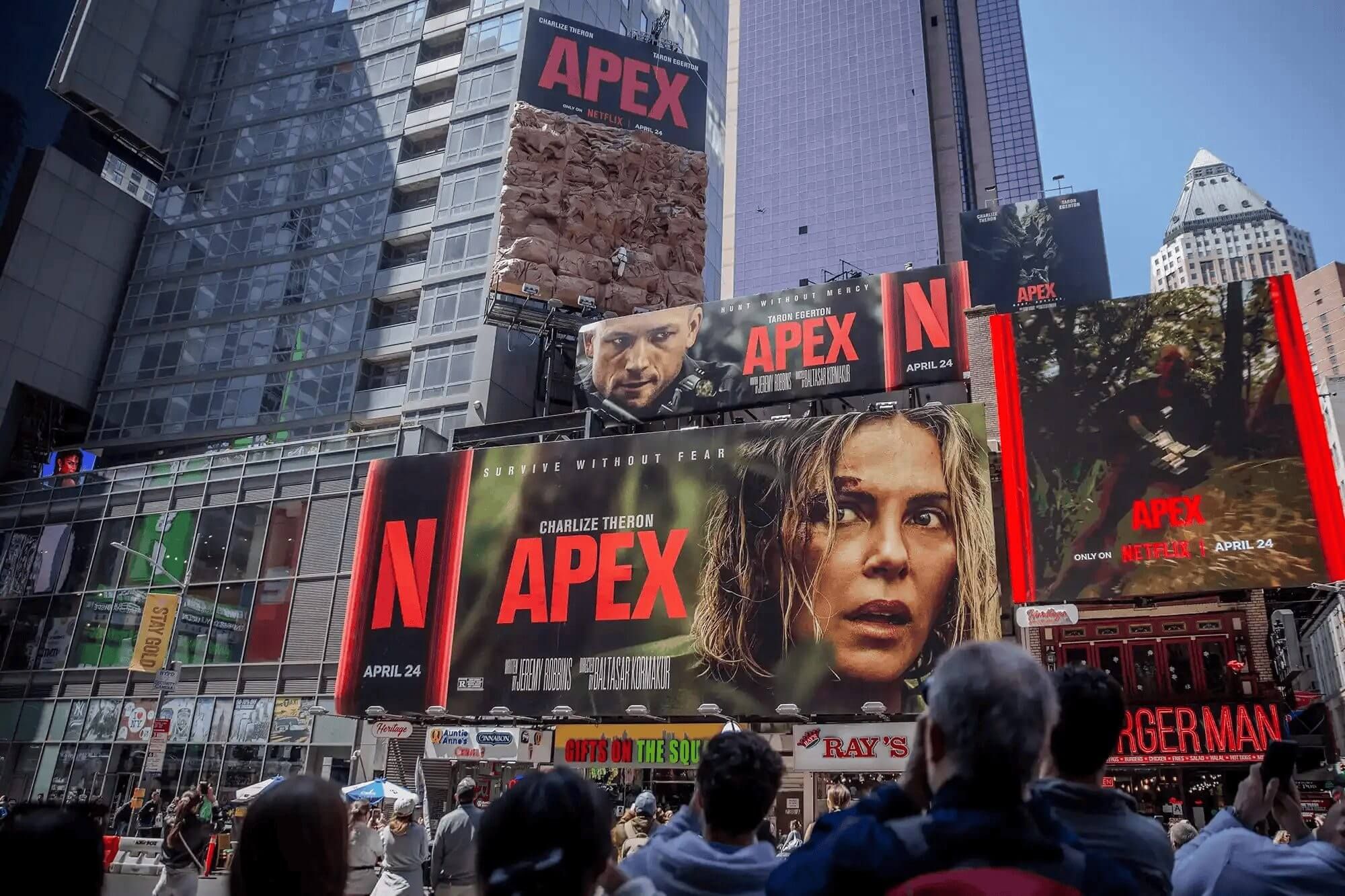 Netflix faz Charlize Theron escalar outdoor gigante na Times Square pra promover filme ‘Apex’