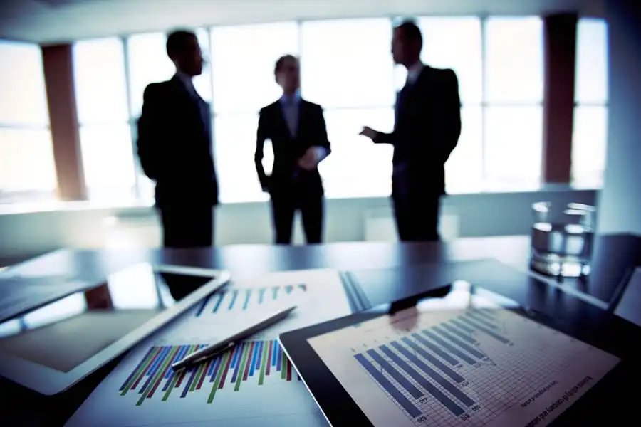 Foto de empresários conversando sobre gráficos e documentos.