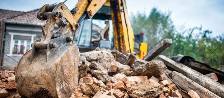 Trator demolindo casa desapropriada para obras de infraestrutura da cidade