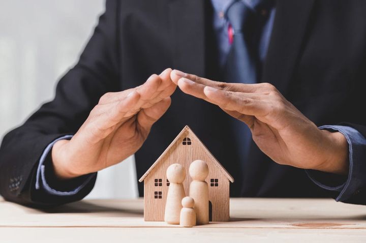 Homem cuidando da maquete de uma casa.