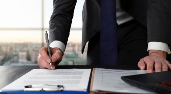 Pessoa assinando documentos para Averbação de imóveis.