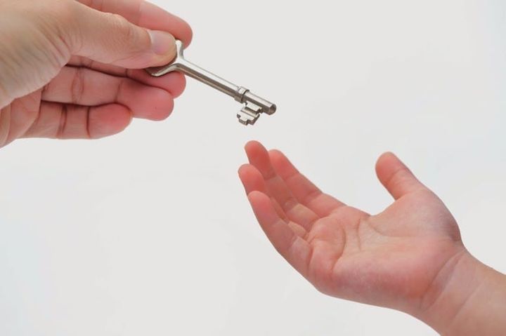 Uma mão entregando uma chave a outra mão.