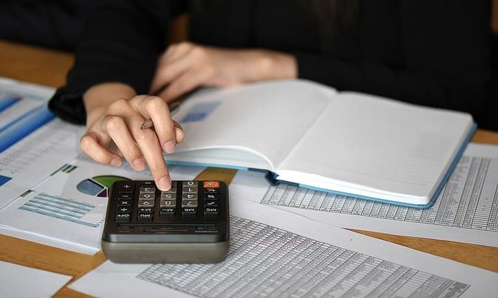 Pessoa calculando dados de planilha de gastos.