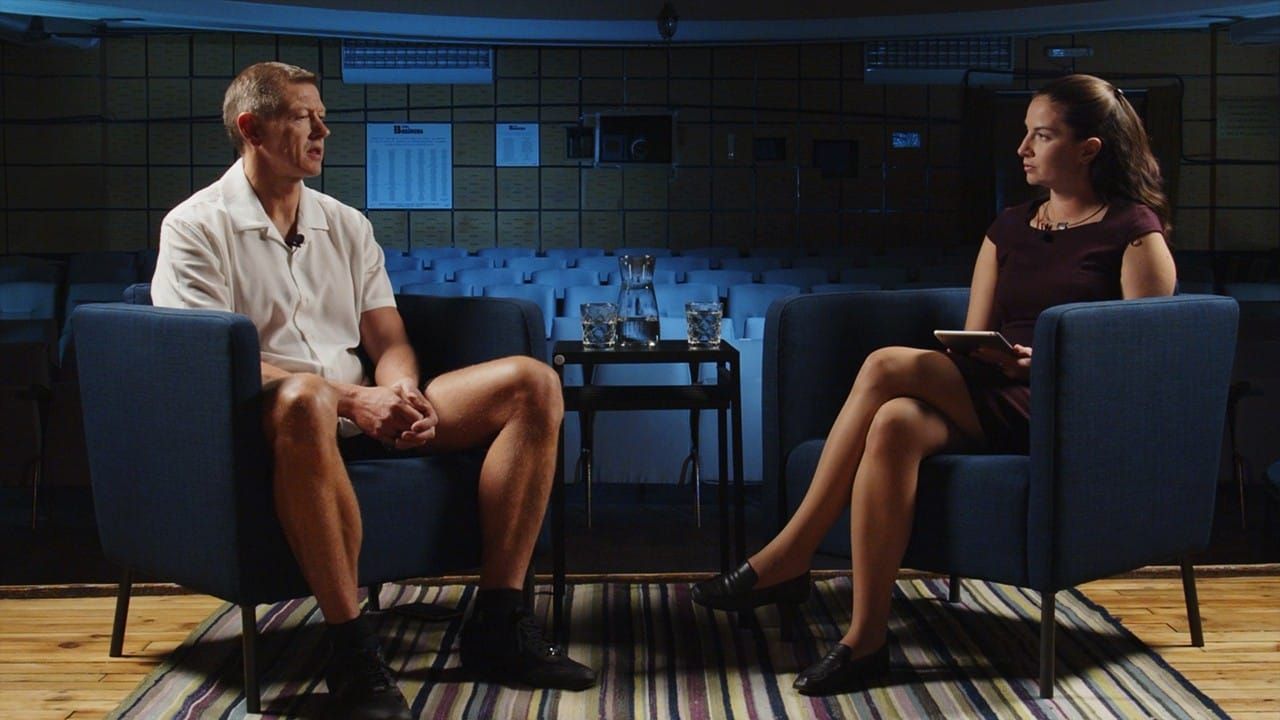 Motivational speaker Peter Sage and podcast host Irina Obushtarova talk sitting in blue chairs